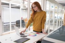 Jovem designer gráfico feminino usando laptop no escritório — Fotografia de Stock
