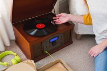 Parte média da mulher tocando um gramofone em casa — Fotografia de Stock