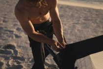 Hombre surfista preparando una cometa en una playa al atardecer - foto de stock
