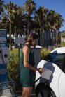 Belle femme recharge voiture électrique à la station de charge — Photo de stock