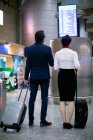 Бізнесмен і жінка, дивлячись на дошку відправлення в аеропорту — стокове фото