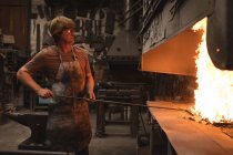 Кузнец нагревает металлический кусок в огне в мастерской — стоковое фото