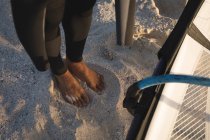 Bassa sezione di surfista maschio in piedi con aquilone sulla spiaggia — Foto stock