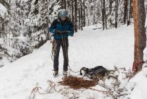 Scalatore di roccia maschio che tiene la corda in montagna innevata durante l'inverno — Foto stock