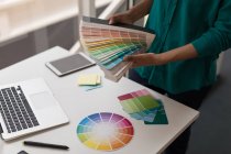 Graphiste femelle tenant des cartes de nuance de couleur dans le bureau — Photo de stock