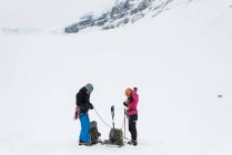 Casal usando arnês em uma montanha coberta de neve durante o inverno — Fotografia de Stock