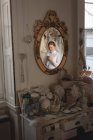 Kaukasische Braut in Brautkleid und Schleier steht vor Spiegel in Vintage-Boutique und benutzt Handy — Stockfoto