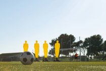 Футбольное снаряжение и футбольный мяч в поле в солнечный день — стоковое фото