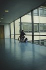 Вид ззаду інвалідний чоловік на інвалідному візку, що дивиться зі скляної панелі — стокове фото