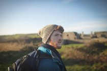 Nachdenklicher männlicher Wanderer steht mit Rucksack auf dem Land — Stockfoto