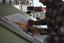 Архитектор работает над проектом чертежа чертежного стола в офисе — стоковое фото