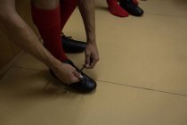Sezione bassa del giocatore di calcio legare il suo merletto scarpa nello spogliatoio — Foto stock