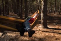 Femme relaxant sur hamac en forêt par une journée ensoleillée — Photo de stock