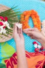 Mid section of woman preparing lei garland in the garden — Stock Photo