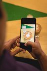 Мужчина щелкает фото кофе с мобильного телефона в кофейне — стоковое фото