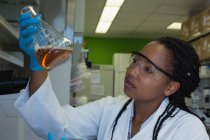 Cientista a verificar uma solução em frasco cónico no laboratório — Fotografia de Stock