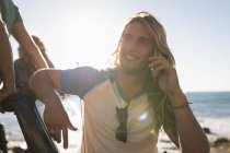 Мужчина разговаривает по мобильному телефону на пляже в солнечный день — стоковое фото