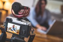 Крупним планом жіночий відеоблогер сидить на дивані під час використання ноутбука — стокове фото