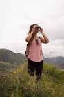 Bella donna guardando attraverso il binocolo in campagna — Foto stock