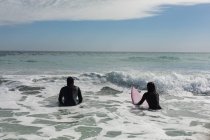 Vista trasera de la pareja de surfistas surfeando en la playa - foto de stock