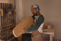 Uomo che esamina uno skateboard in laboratorio — Foto stock