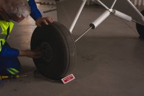 Ingegnere che controlla il pneumatico di un aereo nell'hangar aerospaziale — Foto stock