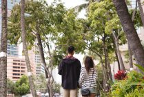 Visão traseira do casal andando juntos na calçada da cidade — Fotografia de Stock