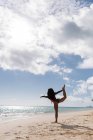 Женщина, занимающаяся на пляже в солнечный день — стоковое фото