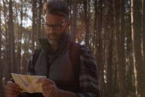 Mann schaut an einem sonnigen Tag auf Landkarte im Wald — Stockfoto