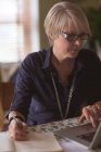 Зріла жінка використовує ноутбук під час написання в щоденнику вдома — стокове фото