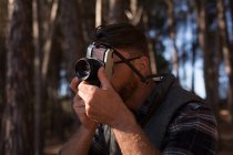 Крупним планом чоловік натискає фотографію з старовинною камерою в лісі — стокове фото