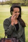 Усміхнена жінка говорить по скляному мобільному телефону в парку — стокове фото