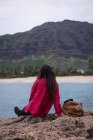 Rückansicht einer Frau, die sich auf einem Felsen am Strand entspannt — Stockfoto