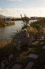 Seniorenpaar entspannt sich an einem sonnigen Tag auf einer Bank am Flussufer — Stockfoto