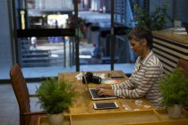 Зріла бізнес-леді використовує ноутбук за столом в офісі — стокове фото