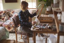 Artista feminina pintura imagem sobre tela na sala de estar em casa — Fotografia de Stock