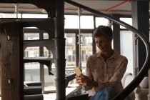 Geschäftsfrau benutzt Handy auf Treppe im Büro — Stockfoto