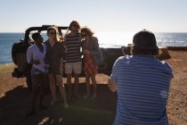 Amigo masculino clicando fotos de amigos com câmera na praia — Fotografia de Stock