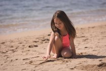 Entzückendes Mädchen spielt auf Sand am Strand — Stockfoto