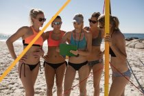 Entrenadora de voleibol femenina interactuando con jugadoras en la playa - foto de stock