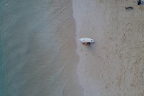 Воздух женщины с доской для серфинга, сидящей на пляже — стоковое фото
