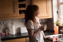 Продумана жінка, що має каву на кухні вдома — стокове фото