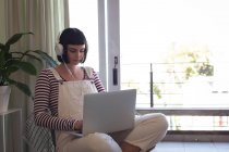 Young woman with headphones using laptop at home — Stock Photo