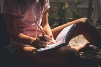 Жінка пише на щоденнику у вітальні вдома — стокове фото