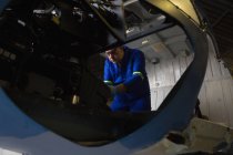 Engineer examining cockpit in aerospace hanger — Stock Photo