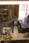 Человек делает скейтборд в мастерской — стоковое фото