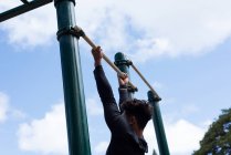 Hombre ejercitándose en barra horizontal en el parque en un día soleado - foto de stock
