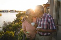Старшая пара целуется дома на балконе — стоковое фото