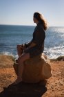 Mulher pensativa sentada em uma rocha na praia — Fotografia de Stock