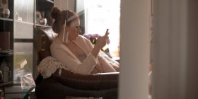 Красива жінка використовує мобільний телефон вдома — стокове фото